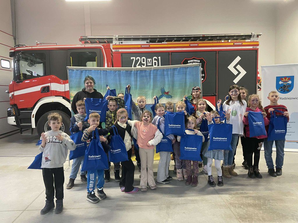 Dzieci ze strażakami na tle samochodu OSP