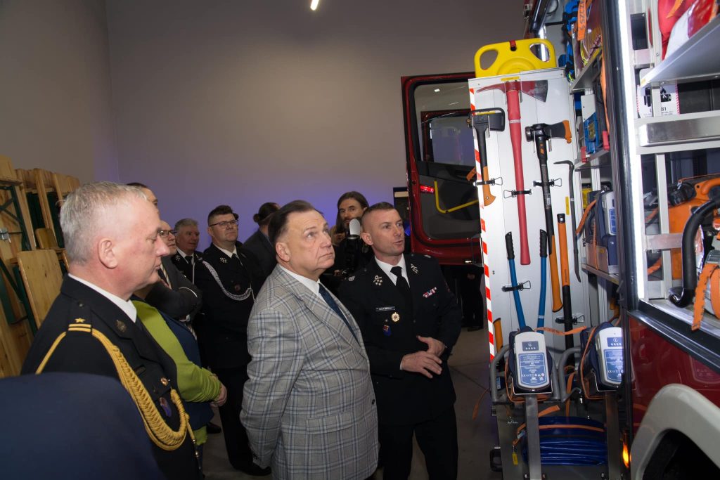 Grupa osób. Osoby oglądają samochód.