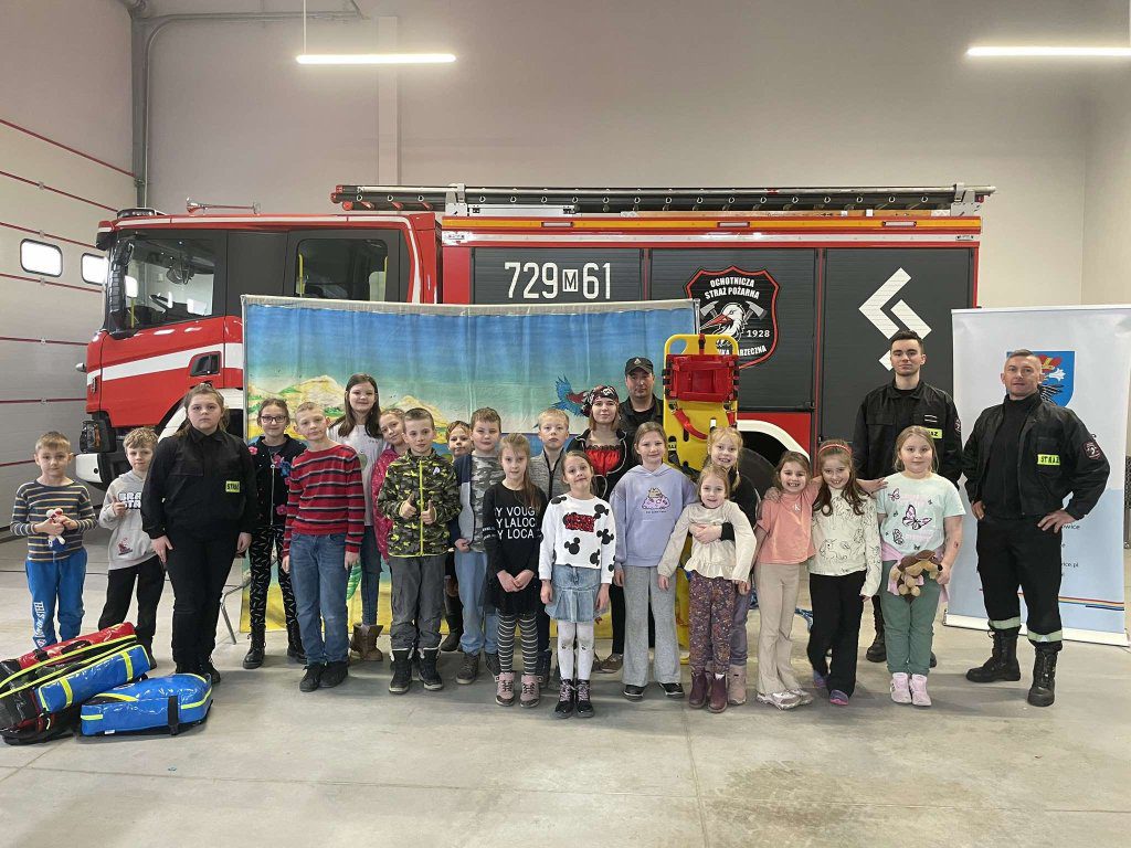 Grupa dzieci ze strażakami na tle samochodu OSP
