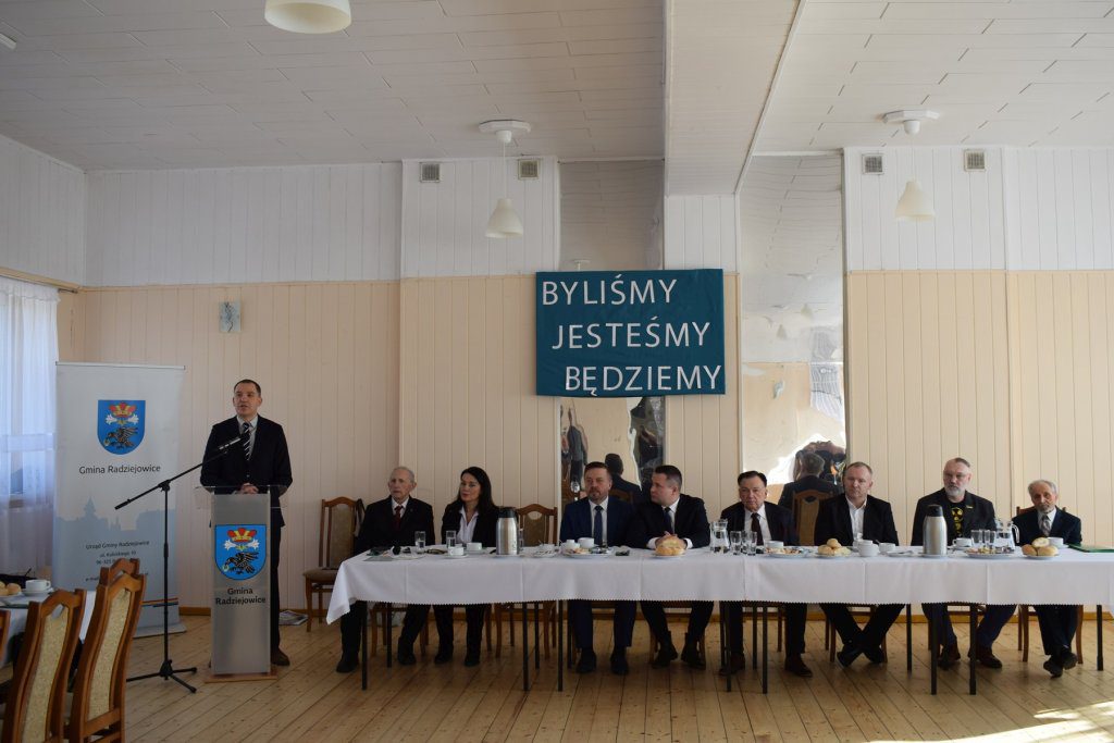 Grupa osób siedzi za stołem.