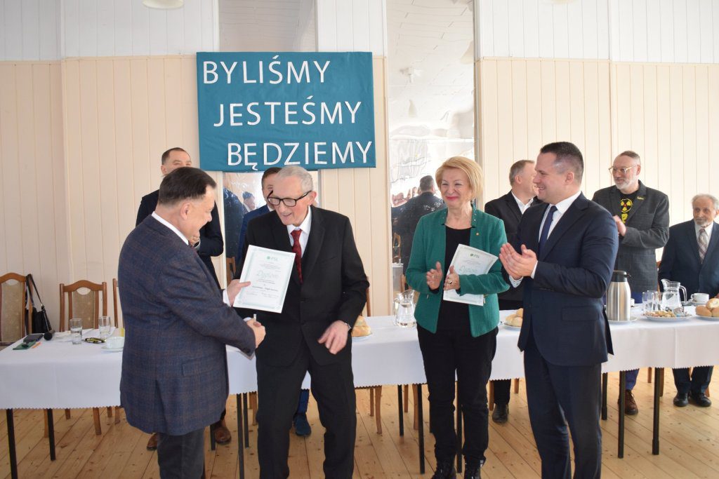 Mężczyzna otrzymuje dyplom honorowy.