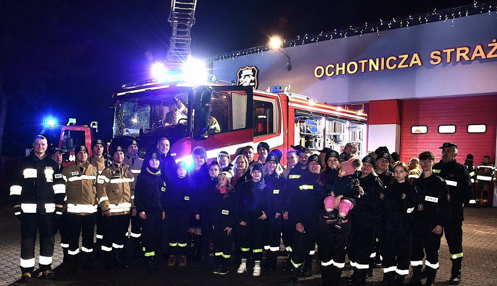 Strażacy pamiątkowe zdjęcie na tle samochodu