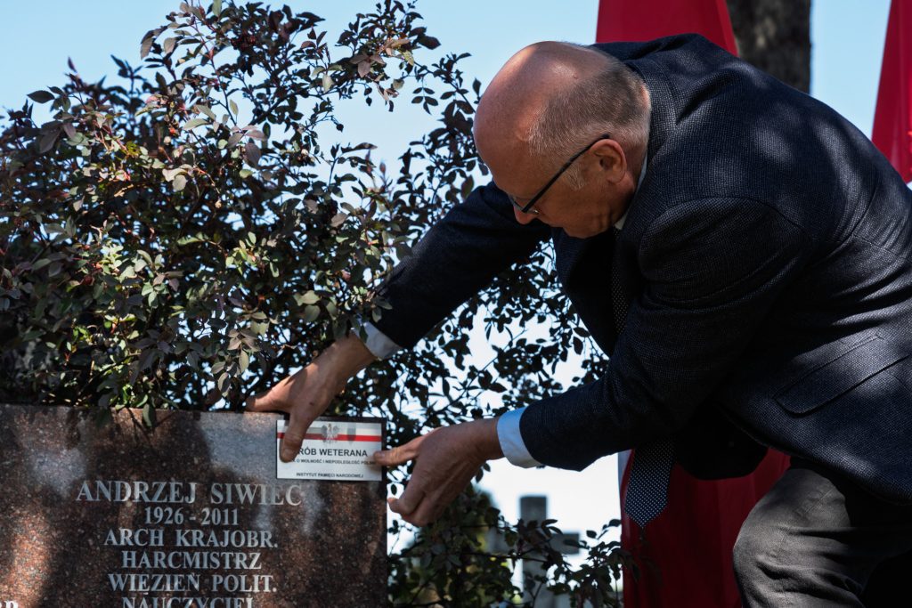 Mężczyzna oznacza mogiłę tabliczkami pamięci „Tobie Polsko”