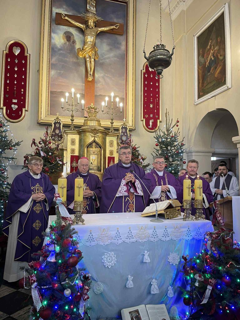 Biskup i księża celebrujący mszę przy ołtarzu w udekorowanym kościele