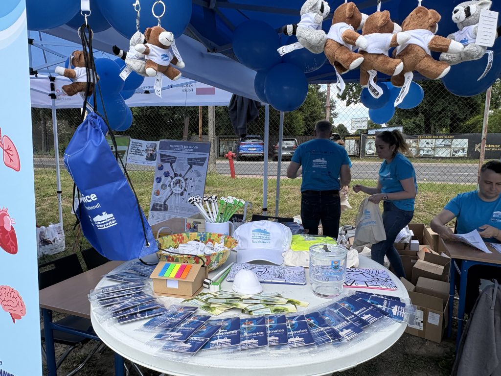 Materiały promocyjne i gadżety programu „Czyste Powietrze” wyłożone na stole w namiocie informacyjnym.
