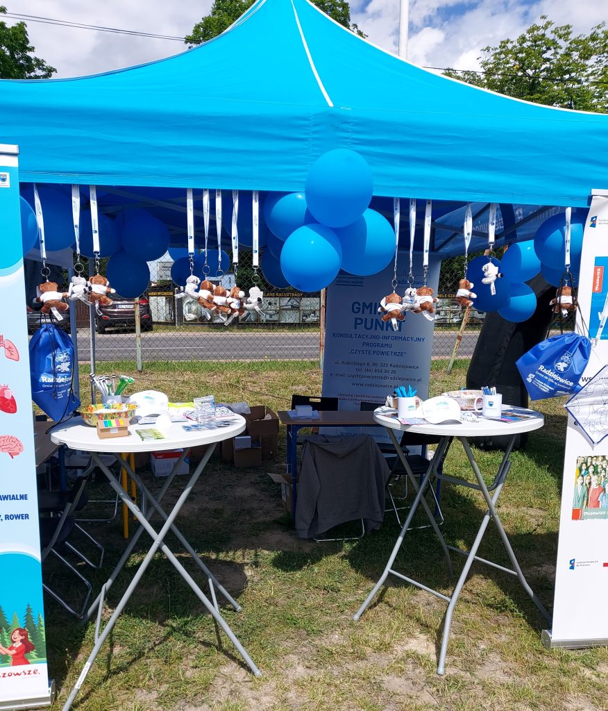 Stoisko programu „Czyste Powietrze” przygotowane podczas wydarzenia plenerowego, ozdobione niebieskimi balonami i materiałami promocyjnymi