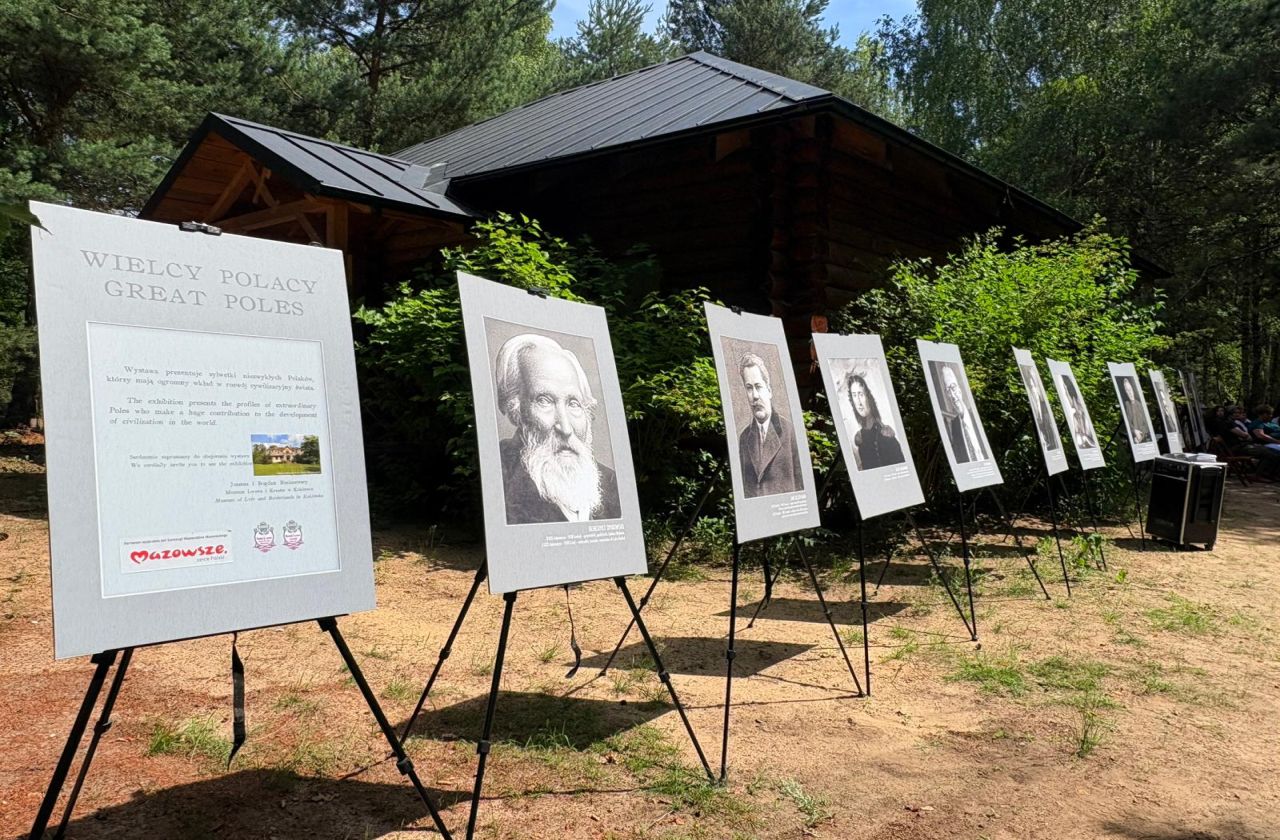 Obraz wyróżniający Plansze wystawy plenerowej „Wielcy Polacy” ustawione przed drewnianym budynkiem Muzeum Lwowa i Kresów w Kuklówce Radziejowickiej