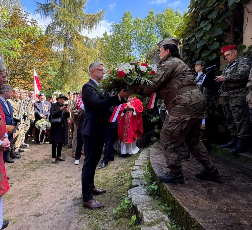 Przekazanie biało-czerwonej wiązanki kwiatów podczas uroczystości patriotycznej