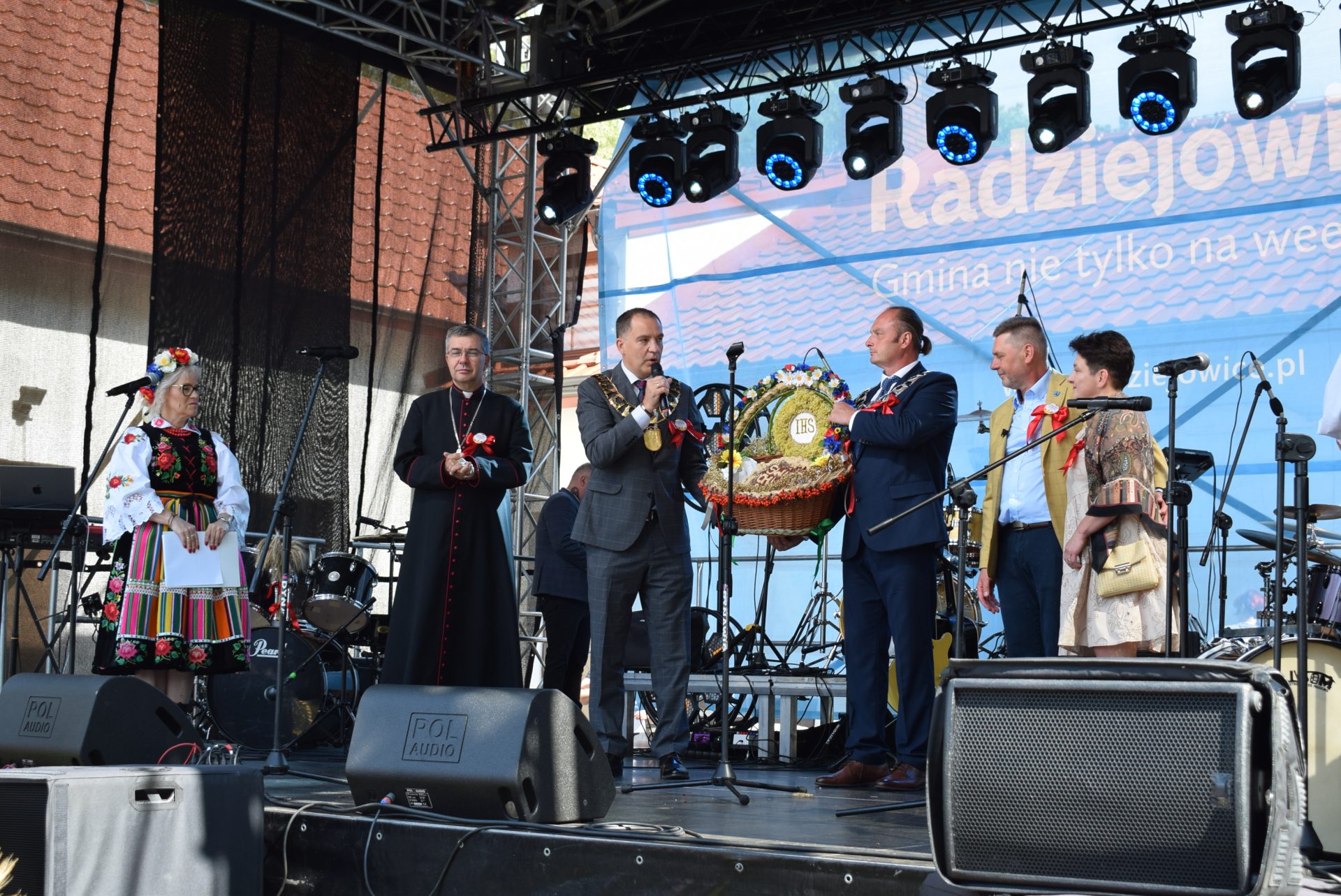 Przedstawiciele władz i uczestnicy uroczystości prezentują wieniec dożynkowy na scenie podczas Święta Chleba w Radziejowicach.
