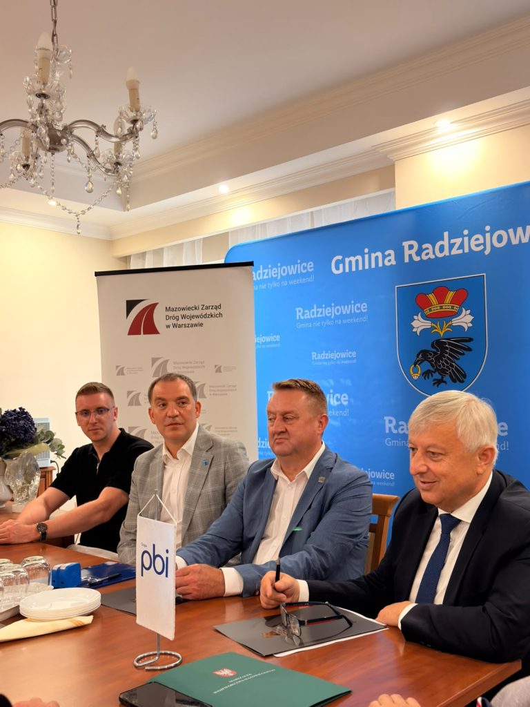 Przedstawiciele Gminy Radziejowice, Mazowieckiego Zarządu Dróg Wojewódzkich i Grupy PBI uczestniczą w spotkaniu przy stole konferencyjnym.