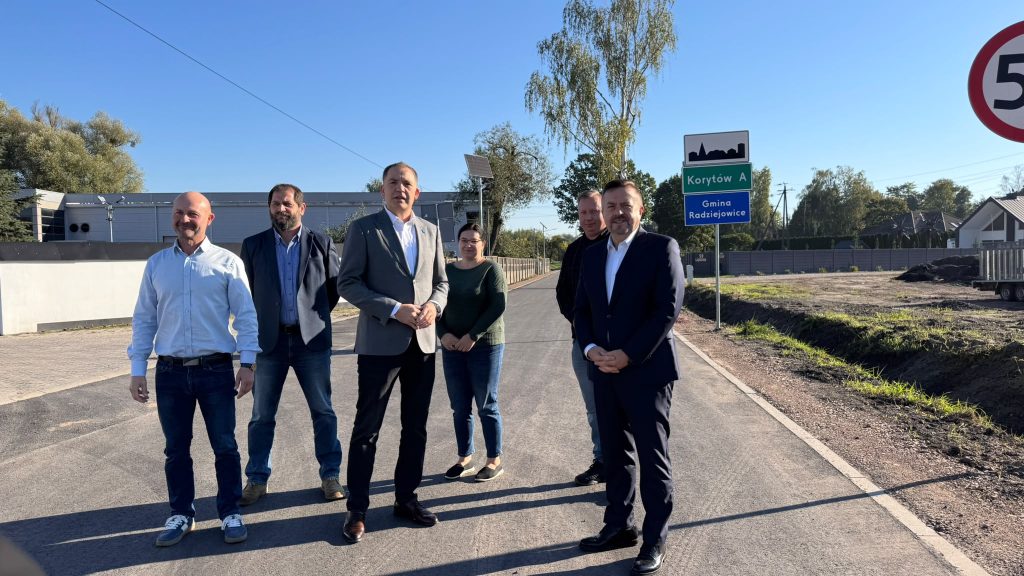 Grupa pięciu osób stojących na nowo wyremontowanej drodze w Korytowie A. W tle widoczny jest znak z nazwą miejscowości i nazwą Gminy Radziejowice.